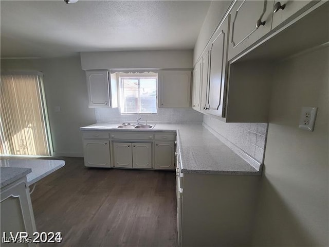 kitchen featuring decorative backsplash, a sink, dark wood-type flooring, and light stone counters
