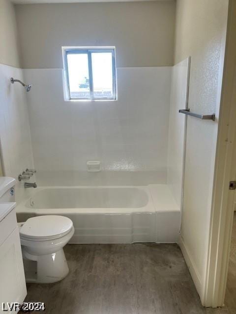 bathroom with toilet, wood finished floors,  shower combination, and vanity