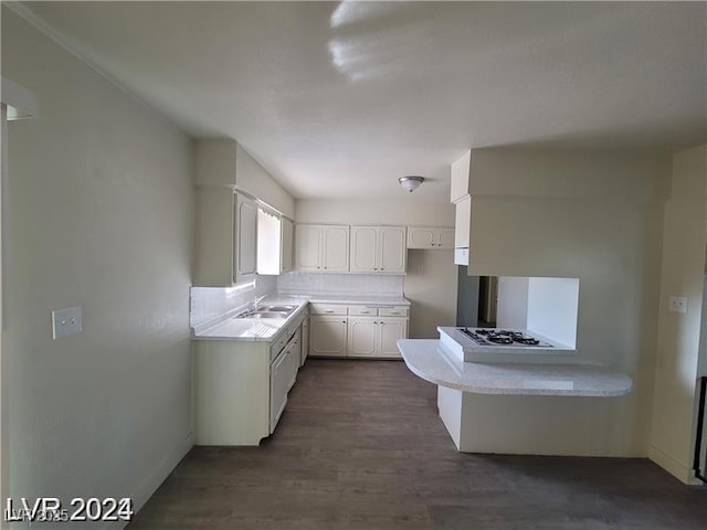 kitchen featuring white cabinetry, light countertops, backsplash, a sink, and dark wood-type flooring