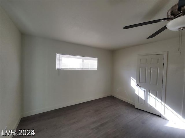empty room with ceiling fan, wood finished floors, and baseboards