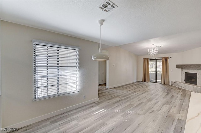 2633 S Durango Dr Unit 201, Las Vegas, NV 89117 - unfurnished living room featuring a chandelier, light wood finished floors, baseboards, and a fireplace