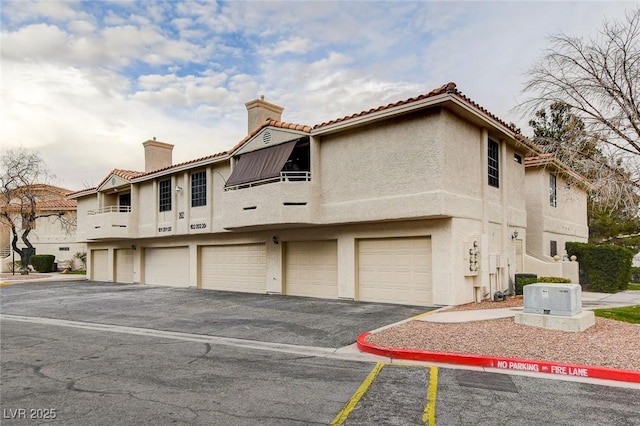 2633 S Durango Dr Unit 201, Las Vegas, NV 89117 - view of front of home with a chimney, stucco siding, driveway, and a garage