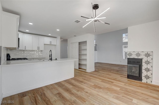 kitchen with a sink, open floor plan, stove, a tile fireplace, and light countertops