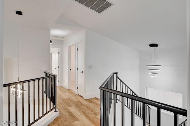 hallway with an upstairs landing, wood finished floors, and baseboards