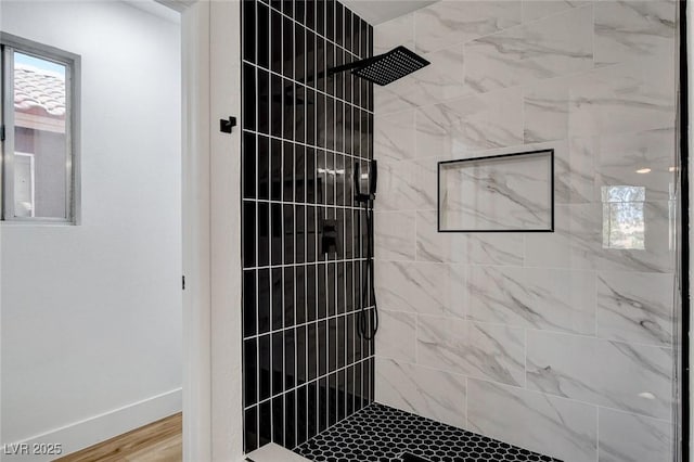 full bathroom featuring a tile shower and baseboards