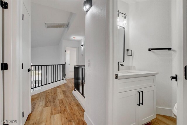 bathroom with wood finished floors, baseboards, vanity, and toilet