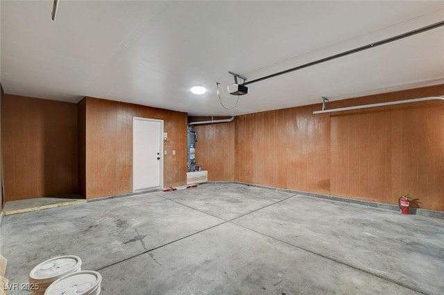 garage with a garage door opener, wood walls, and gas water heater