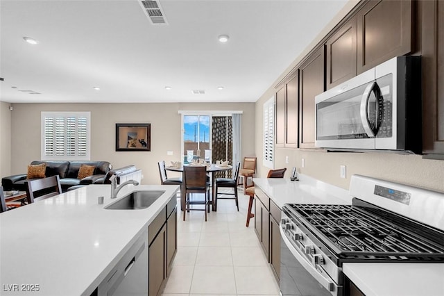 3556 Valley Lily St, North Las Vegas, NV 89032 - kitchen with appliances with stainless steel finishes, a sink, dark brown cabinets, light countertops, and open floor plan
