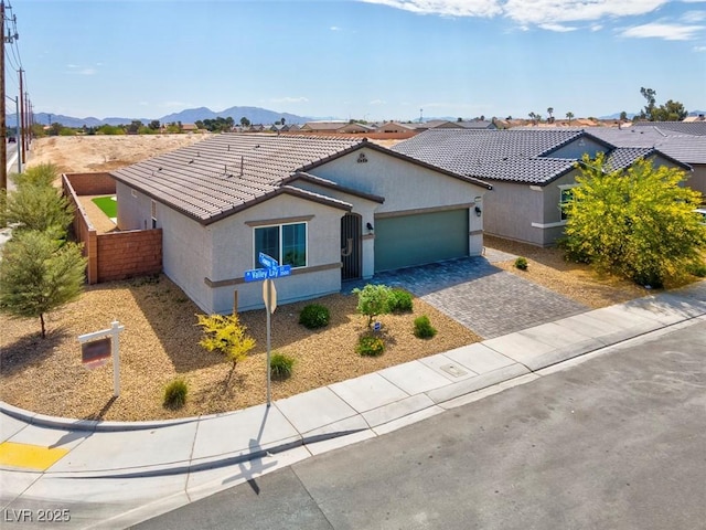3556 Valley Lily St, North Las Vegas, NV 89032 - ranch-style home with a tiled roof, stucco siding, an attached garage, decorative driveway, and a mountain view