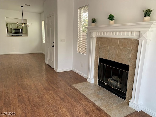 9236 Canalino Dr, Las Vegas, NV 89134 - unfurnished living room featuring a tiled fireplace, wood finished floors, healthy amount of natural light, and baseboards