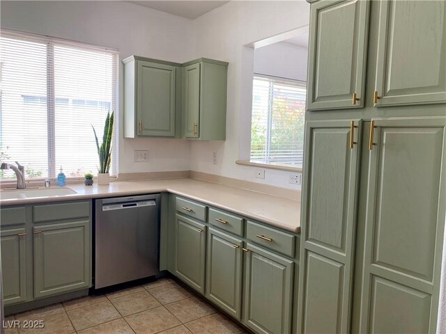 9236 Canalino Dr, Las Vegas, NV 89134 - kitchen with stainless steel dishwasher, a sink, green cabinetry, light tile patterned floors, and light countertops