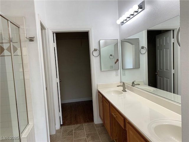 9236 Canalino Dr, Las Vegas, NV 89134 - full bathroom featuring a stall shower, double vanity, a walk in closet, baseboards, and tile patterned flooring