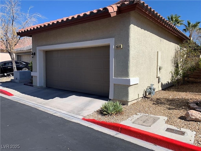9236 Canalino Dr, Las Vegas, NV 89134 - view of property exterior featuring stucco siding, a garage, a tile roof, and driveway