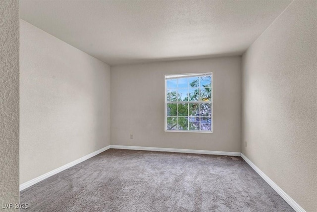 carpeted empty room with a textured wall and baseboards