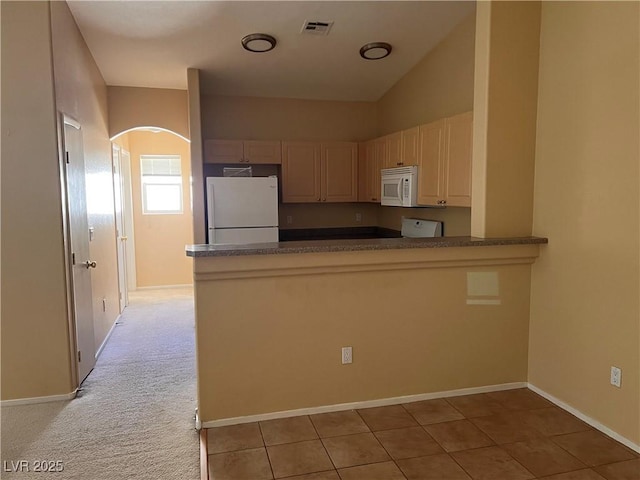 8688 Tomnitz Ave Unit 101, Las Vegas, NV 89178 - kitchen featuring white appliances, arched walkways, a peninsula, dark countertops, and light tile patterned floors