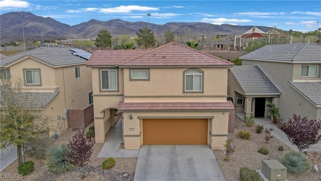 traditional home featuring stucco siding, driveway, a mountain view, an attached garage, and a tile roof