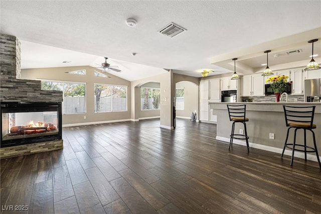 5912 Hollowridge Rd, North Las Vegas, NV 89031 - living area featuring baseboards, arched walkways, a fireplace, dark wood-style floors, and ceiling fan