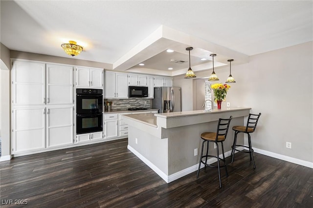5912 Hollowridge Rd, North Las Vegas, NV 89031 - kitchen with black appliances, a peninsula, dark wood-style flooring, a kitchen bar, and recessed lighting