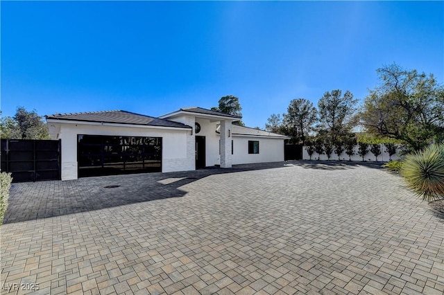 view of front facade featuring stucco siding, fence, a garage, and decorative driveway
