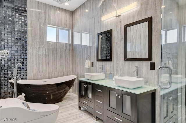 full bathroom with tile walls, a stall shower, double vanity, and a freestanding tub