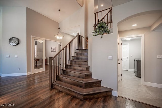 11112 Pine Greens Ct, Las Vegas, NV 89144 - staircase with washer / clothes dryer, arched walkways, wood finished floors, baseboards, and a towering ceiling
