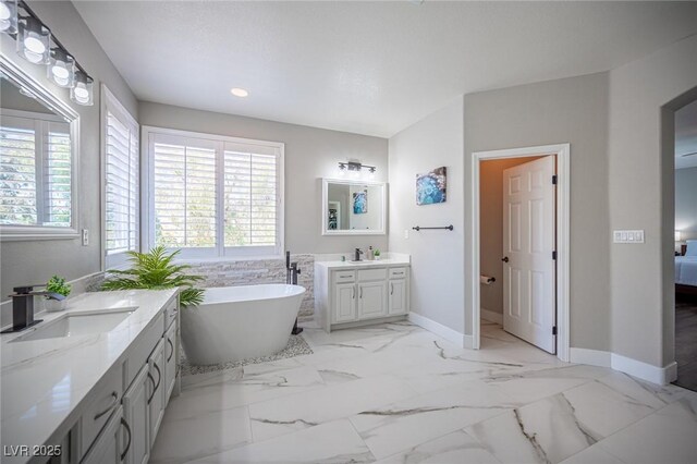 11112 Pine Greens Ct, Las Vegas, NV 89144 - bathroom featuring healthy amount of natural light, a freestanding bath, recessed lighting, two vanities, and baseboards