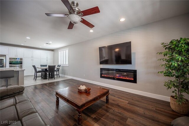 11112 Pine Greens Ct, Las Vegas, NV 89144 - living room with baseboards, a glass covered fireplace, dark wood-type flooring, recessed lighting, and ceiling fan