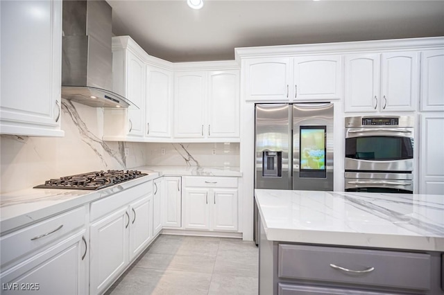 11112 Pine Greens Ct, Las Vegas, NV 89144 - kitchen featuring wall chimney range hood, stainless steel appliances, light stone counters, and white cabinetry