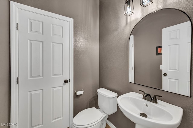 11908 Menchaca Ln, Las Vegas, NV 89138 - half bathroom featuring a sink, toilet, a textured wall, and baseboards