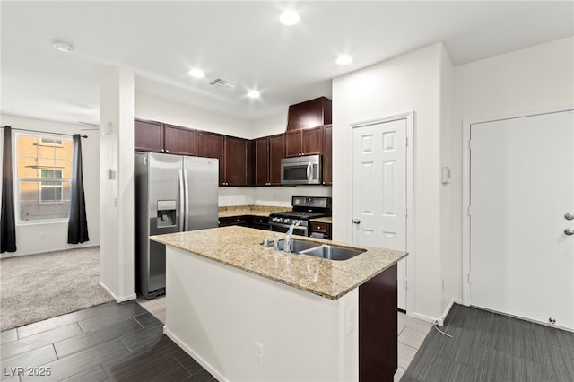 4533 Lime Straight Dr, Las Vegas, NV 89115 - kitchen with appliances with stainless steel finishes, dark brown cabinets, an island with sink, light stone countertops, and a sink