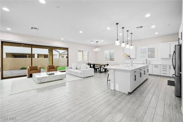 717 Monroe Hill Pl, Henderson, NV 89011 - kitchen featuring freestanding refrigerator, a breakfast bar area, white cabinets, a kitchen island, and recessed lighting