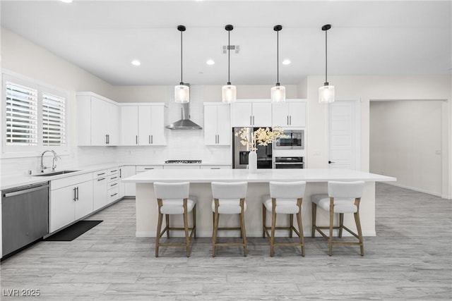 717 Monroe Hill Pl, Henderson, NV 89011 - kitchen featuring appliances with stainless steel finishes, a sink, wall chimney range hood, a center island, and backsplash