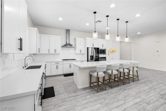 717 Monroe Hill Pl, Henderson, NV 89011 - kitchen featuring appliances with stainless steel finishes, wall chimney range hood, a sink, a breakfast bar, and a center island