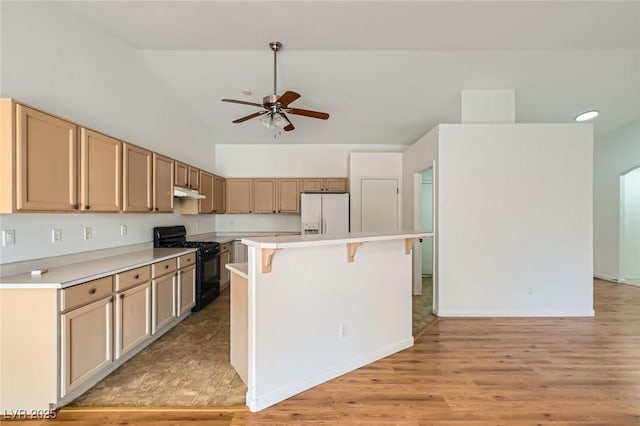 3912 Branchwood Dr, North Las Vegas, NV 89032 - kitchen with black gas range, white refrigerator with ice dispenser, ceiling fan, a kitchen breakfast bar, and under cabinet range hood