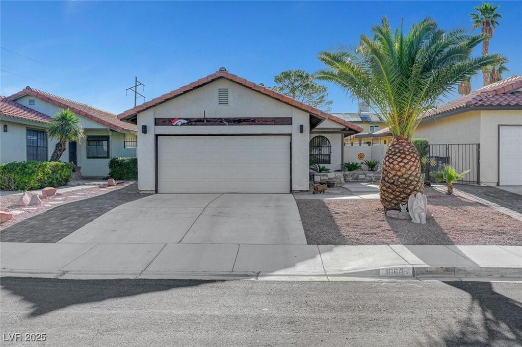 1060 Neil Armstrong Cir, Las Vegas, NV 89145 - view of front of home featuring a garage, stucco siding, concrete driveway, and a tiled roof