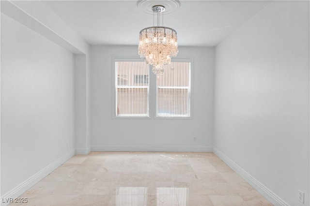 spare room with a chandelier and baseboards
