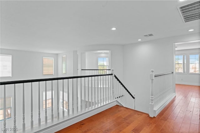 hall with an upstairs landing, hardwood / wood-style flooring, plenty of natural light, recessed lighting, and baseboards