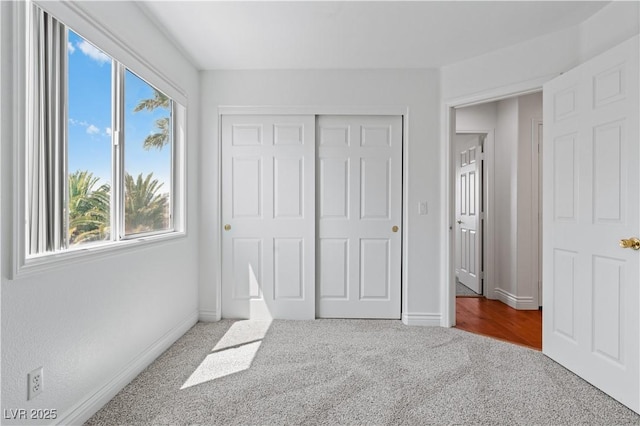 unfurnished bedroom with carpet flooring, baseboards, and a closet