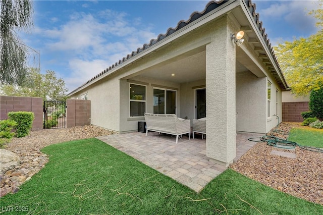 back of property featuring stucco siding, a gate, a patio, and a tile roof