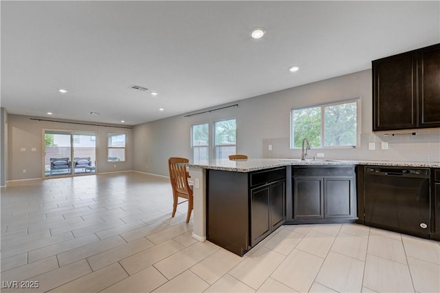 kitchen with black dishwasher, a sink, open floor plan, healthy amount of natural light, and recessed lighting