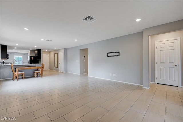 unfurnished living room with recessed lighting and baseboards