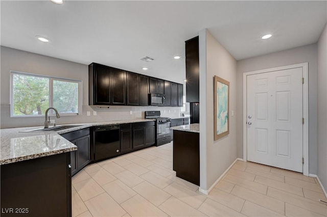 kitchen featuring black appliances, a sink, light stone countertops, decorative backsplash, and recessed lighting