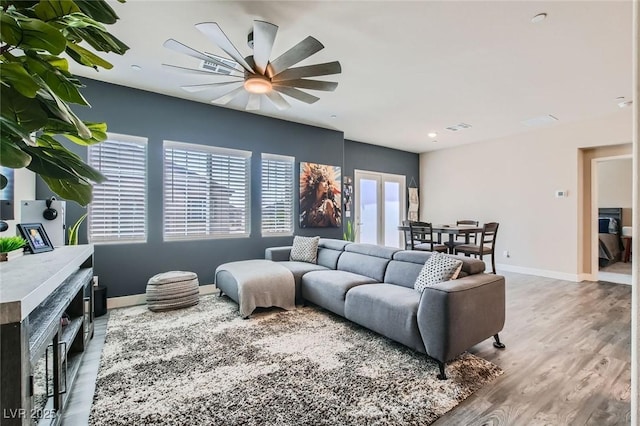 living area featuring wood finished floors, baseboards, and a ceiling fan