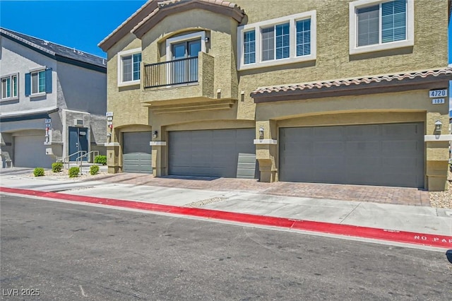 view of property with stucco siding, an attached garage, and a tile roof