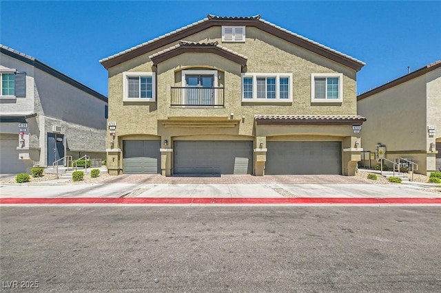 view of property with a garage, stucco siding, driveway, and a balcony
