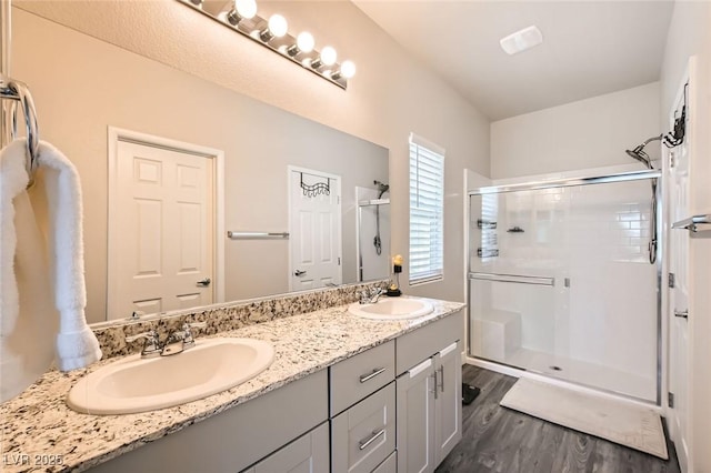 full bath with a stall shower, wood finished floors, and double vanity