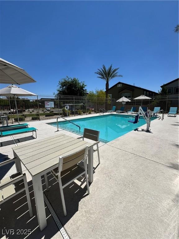 community pool with a patio area and fence