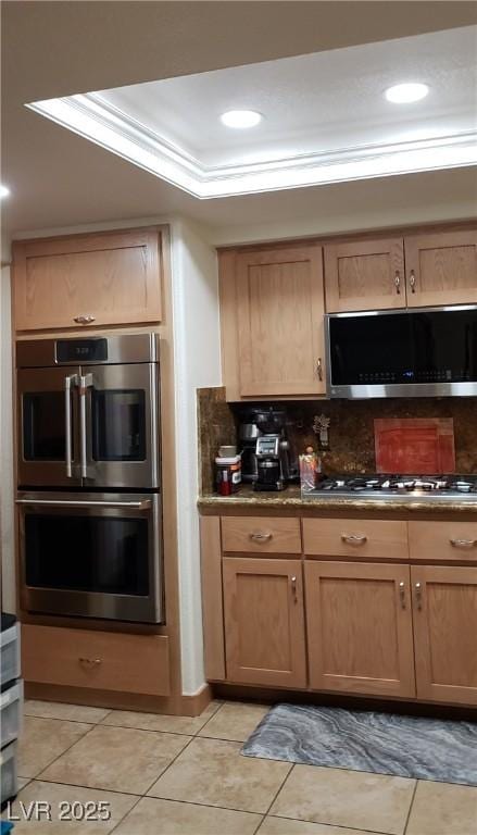 kitchen featuring stainless steel appliances, light tile patterned floors, tasteful backsplash, recessed lighting, and a tray ceiling