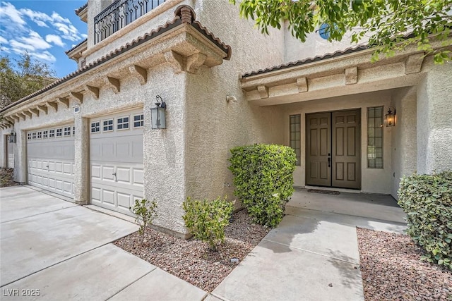 doorway to property featuring driveway, stucco siding, an attached garage, and a tile roof