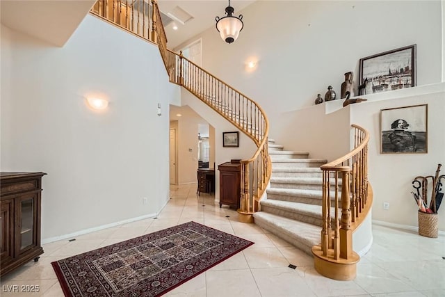 foyer featuring a high ceiling, stairway, light tile patterned floors, and baseboards